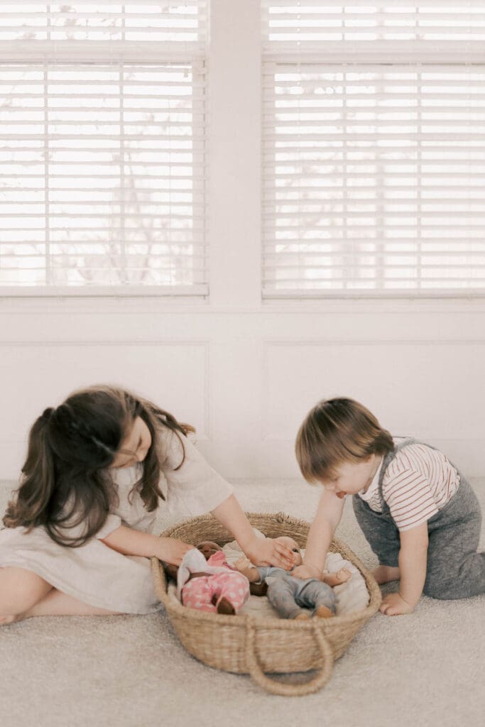 Brother and sister prepare for their twin siblings by taking care of their baby dolls during in-home maternity session in Kansas City 