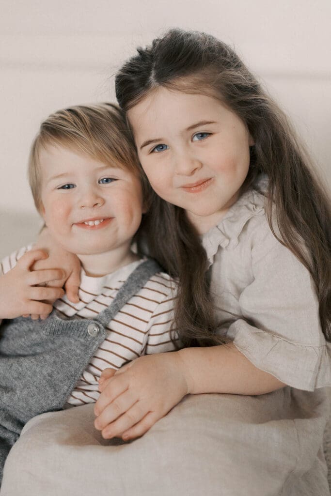 Big brother and sister smile at the camera during family's in home maternity session in Kansas CIty 